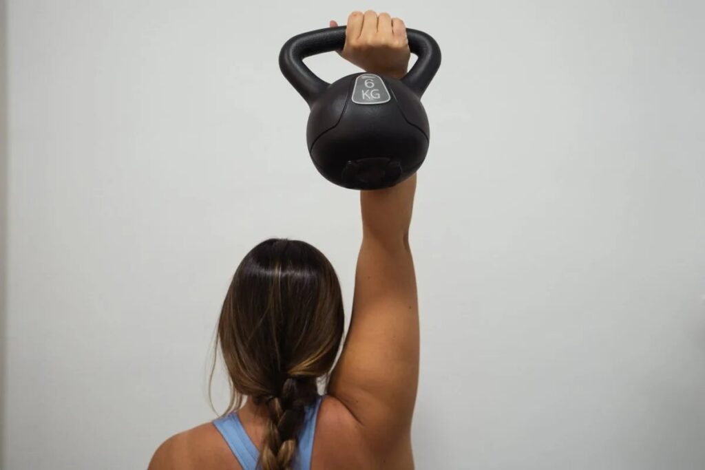 Mujer entrenando con kettlebell para recuperar fuerza antes de volver a correr tras el parto en Clínica Restaura, Villalbilla